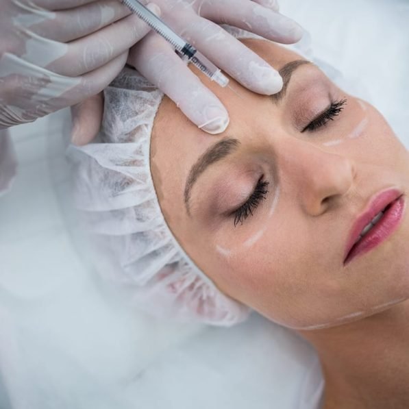 Woman with marked face receiving botox injection
